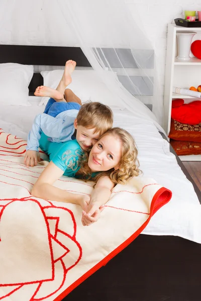 Jonge vrouw met haar zoon tot op bed — Stockfoto