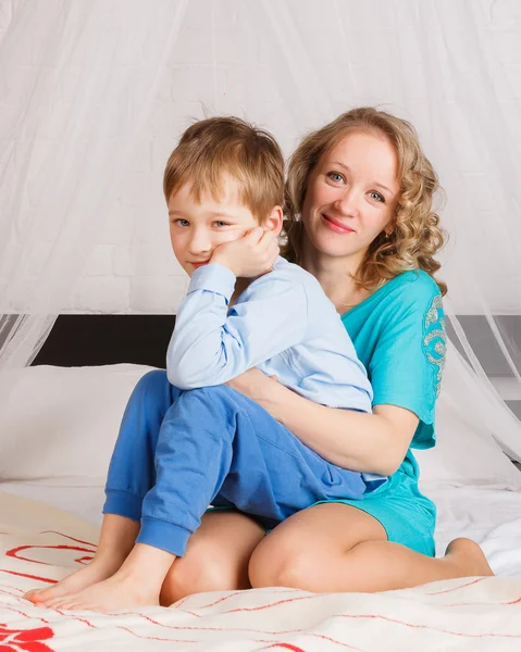 Mutter und ihr Sohn sitzen auf großem Bett — Stockfoto