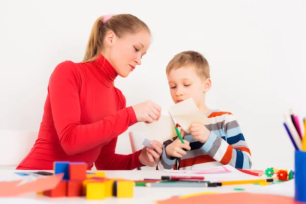 Mutter hilft ihrem Kind beim Papierschneiden — Stockfoto