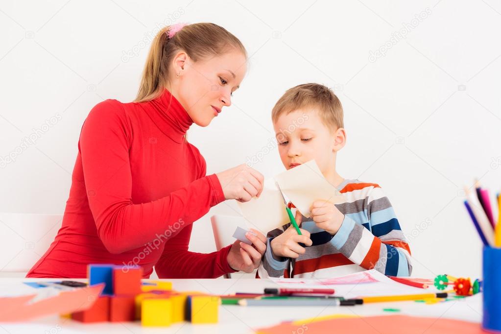 Mother helping her child to cut paper