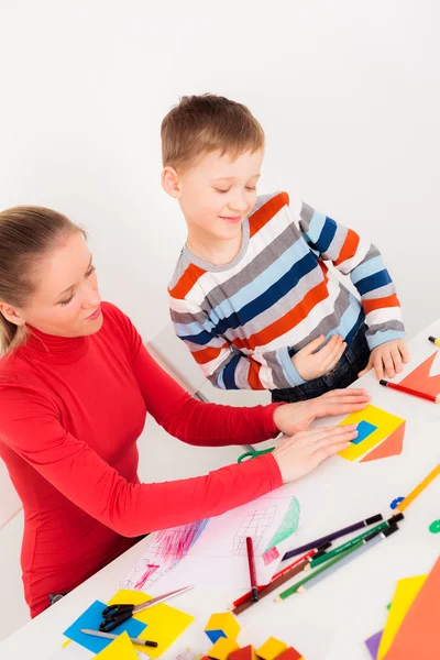 Äiti auttaa poikaansa tekemään talon paperista — kuvapankkivalokuva