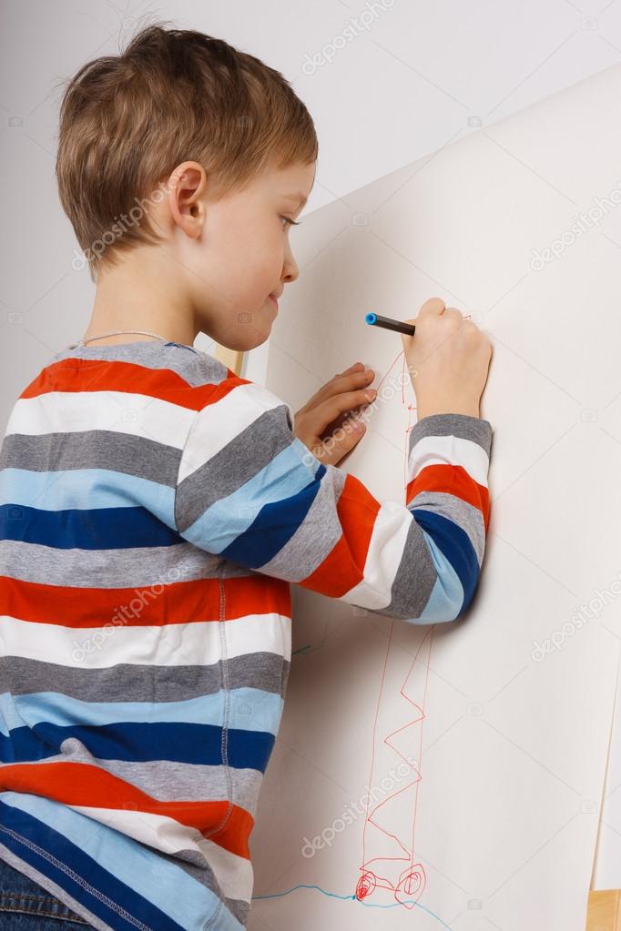 Little boy drawing with pencil on easel
