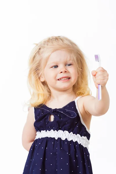 Vacker blond haired flicka tittar på tandborste i handen — Stockfoto