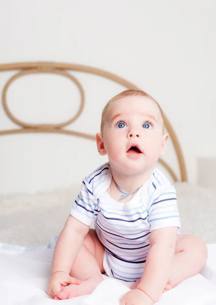 Cute boy sitting on bed Stock Photo