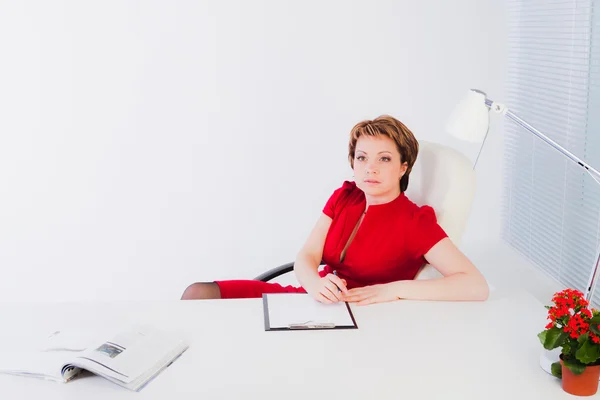 Business woman sitting by white desk — Stock Photo, Image