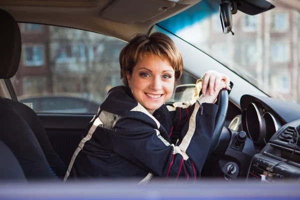 Lächelnde Frau sitzt in neuem Auto — Stockfoto