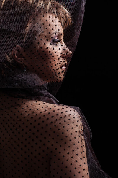 Close up profile portrait of sad woman in black transparent dress