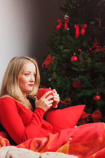 Mujer agradable se sienta en silla redonda con taza roja —  Fotos de Stock