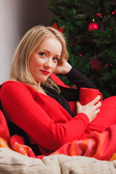 Pěkná žena, sedící v křesle s červeným pohár — Stock fotografie