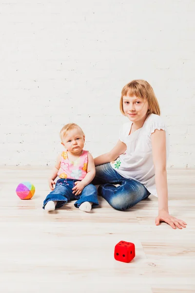 Schwestern sitzen auf Holzboden — Stockfoto