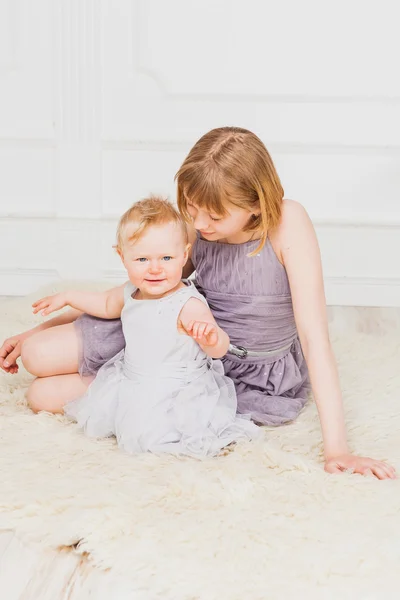 Cute baby girl sitting with her older sister — Stock Photo, Image