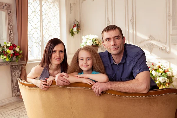 Família agradável de três olhando para a câmera e sorrindo — Fotografia de Stock