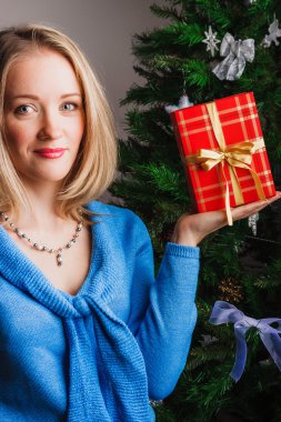 Sarışın kadın kırmızı hediye kutusu elinde tutar.