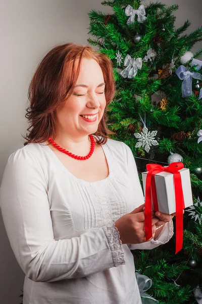 Happy woman holding present with closing eyes — Stock Photo, Image