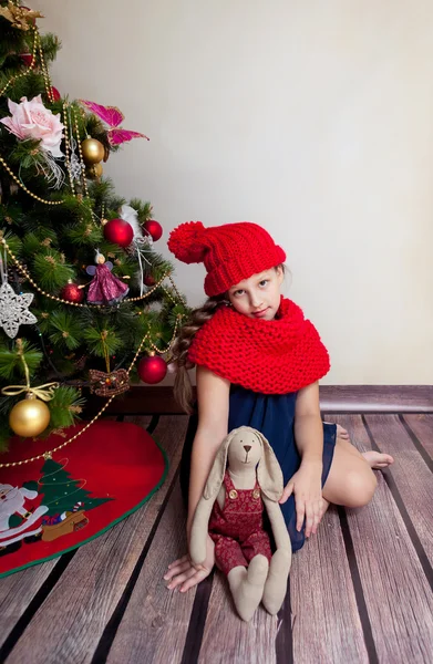 Χαριτωμένο κορίτσι που κάθεται με το παρόν κάτω από το χριστουγεννιάτικο δέντρο — Φωτογραφία Αρχείου