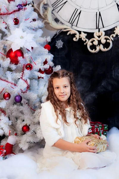 Meisje, zittend met mooi cadeau onder de kerstboom — Stockfoto