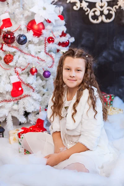 Gadis manis duduk di dekat pohon Natal Stok Foto