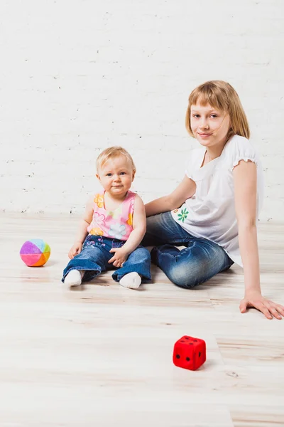 Süßes Mädchen sitzt mit ihrer kleinen Schwester — Stockfoto