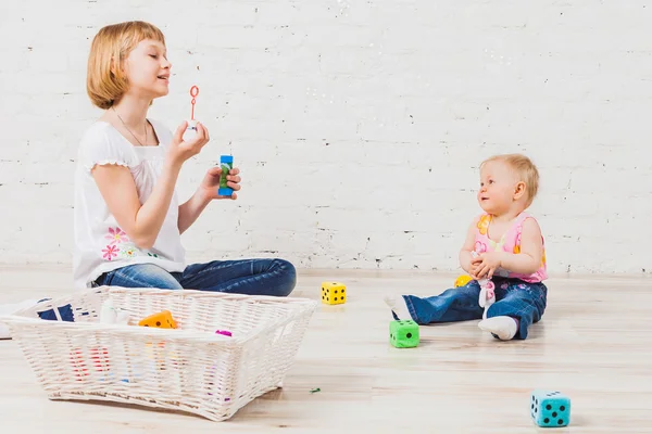 Krásná dívka roztrhá bubliny na její malé sourozence — Stock fotografie