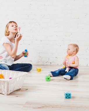 Katta oturan ve kabarcıklar üfleme iki kız kardeşi