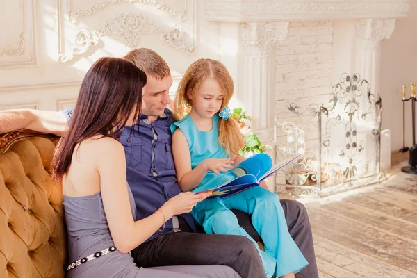 Glad familj läsa bok om soffa — Stockfoto