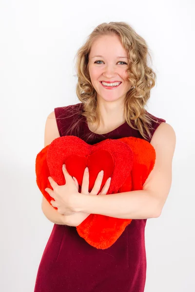 Carino donna bionda in piedi con cuscini decorativi rossi — Foto Stock