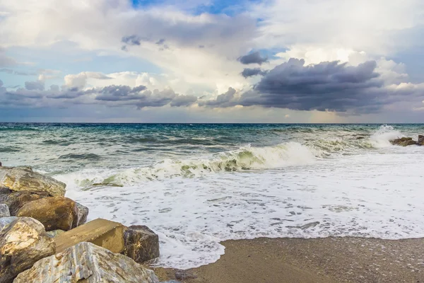 Spiaggia rocciosa con vista mare, onde d'acqua e nuvole scure sul cielo — Foto Stock