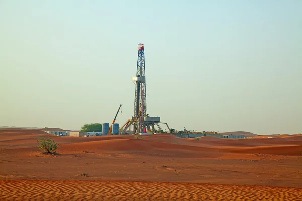 Pôr do sol sobre o campo de petróleo na areia vermelha — Fotografia de Stock