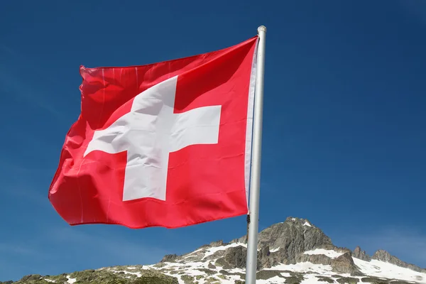 Swiss flag over rocky cliffs — Stock Photo, Image