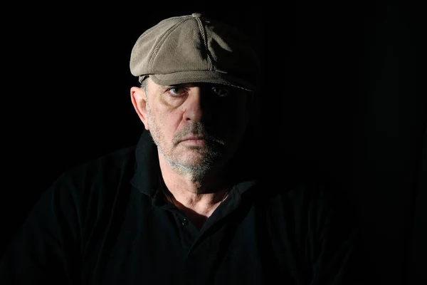 Portrait of elderly man in black clothes on a black background.