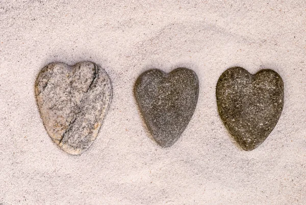 Fila de corazones de piedra en la arena — Foto de Stock