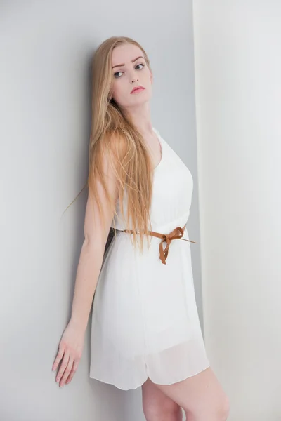 Duvara yaslanmış beyaz elbise giyen kadın — Stok fotoğraf