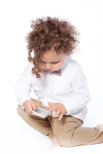 Lockiger kleiner Junge wischt mit dem Handy — Stockfoto