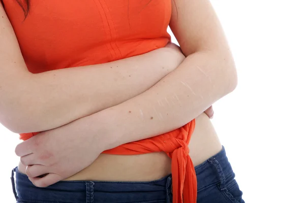 Vrouw in oranje Shirt Crossing Arm bij haar maag — Stockfoto