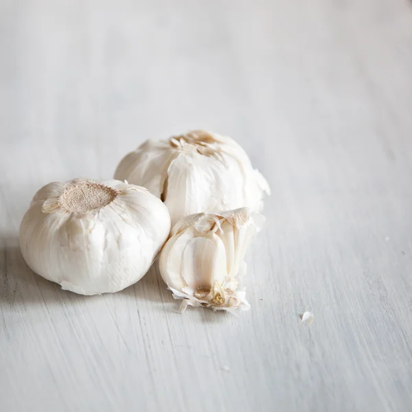 Aglio biologico intero e spicchi sullo sfondo di legno — Foto Stock