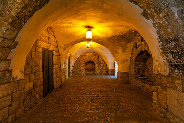 Ancient stone arched passage illuminated with lanterns in Old City of Jerusalem, Israel.
