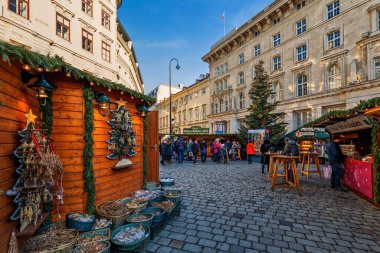 VİANNA, AUSTRIA - 4 Aralık 2019: Avusturya 'nın Viyana kentindeki ünlü geleneksel Noel pazarında ahşap kulübelerin ve ahırların arasında yürüyüp parke ve hediyelik eşya satan insanlar.