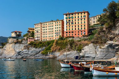 İtalya 'nın Liguria kentindeki Camogli köyünde mavi gökyüzünün altında küçük körfez, tekne ve renkli evler görülüyor..
