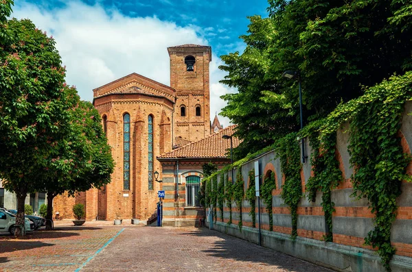 Eski Alba, Piedmont, Kuzey İtalya 'daki dar kaldırım taşı caddesi ve tuğla Katolik kilisesi manzarası.