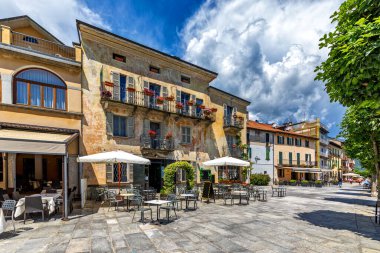 Cannobio 'daki eski evler ve açık hava restoranı boyunca gezinti manzarası - Piedmont, İtalya' da Maggiore Gölü kıyısında küçük bir kasaba.