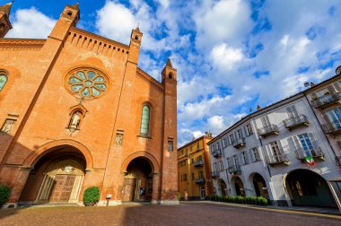 San Lorenzo Cathedral and old houses on cobblestone town square under beautiful sky in Alba, Piedmont, Northern Italy.