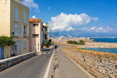 Antibes 'te mavi gökyüzü altında evler ve Akdeniz kıyıları boyunca yaya geçidi ve dar şehir yolu - Fransız Rivierası' nda şehir.