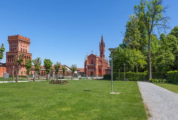 Grön gräsmatta, kyrkan och medeltida torn i Pollenzo, Italien. — Stockfoto