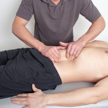 Masaj terapisti karın masajı yapıyor.