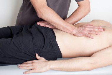 Masaj terapisti karın masajı yapıyor.