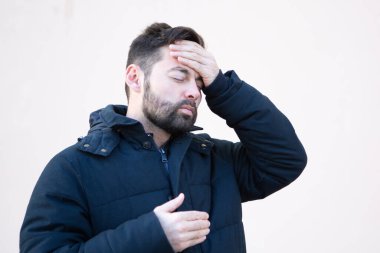 Açık havada baş ağrısı olan kışlık ceketli bir adam.