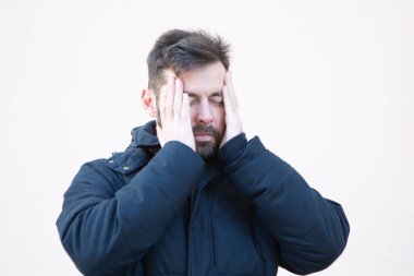 Açık havada baş ağrısı olan kışlık ceketli bir adam.