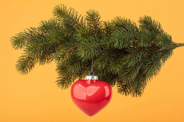 Rode Decoratieve Kerst Hart Opknoping Een Sparren Tak Oranje Achtergrond — Stockfoto