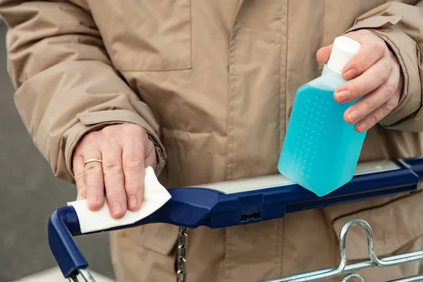 男人的手拿着一个装有消毒剂的塑料瓶 因为用购物车的把手可以消毒 — 图库照片