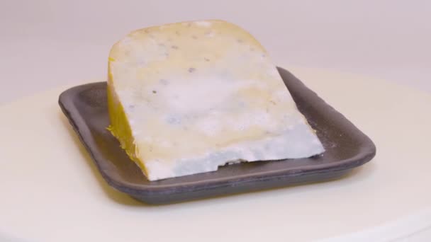 ターンテーブル上で回転する黒い発泡スチロールプレート上のカビチーズのピース — ストック動画